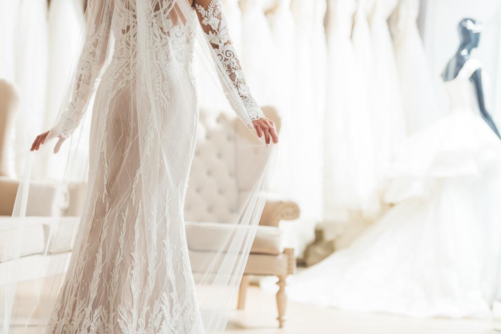 Обрізаний вид на наречену в мереживному платті в весільному салоні
 - Фото, зображення