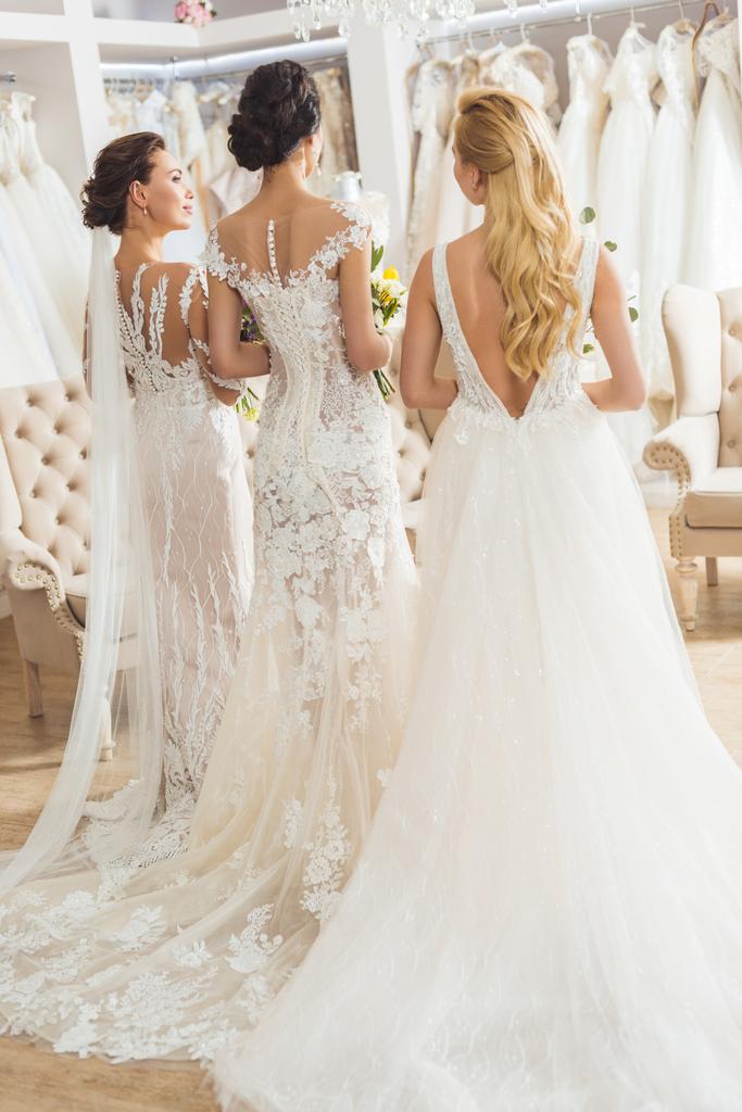 Rear view of brides with bouquets in wedding atelier - Photo, Image