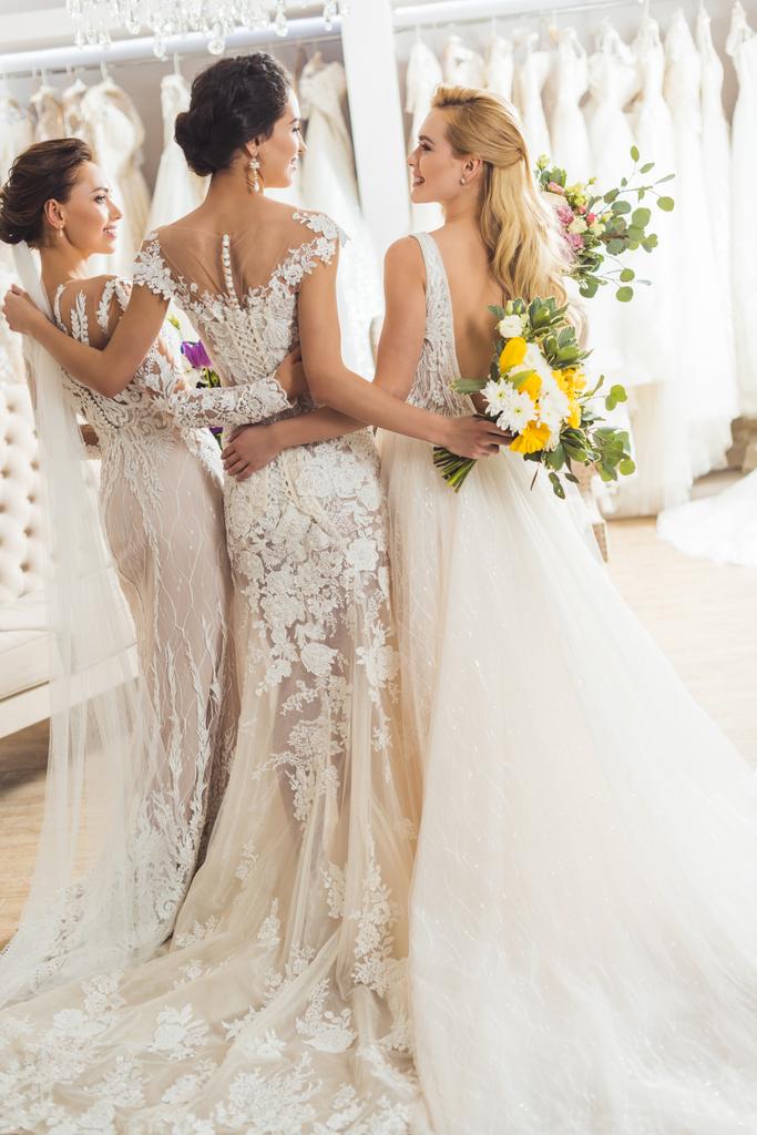 Mujeres atractivas en vestidos de novia abrazando en la tienda de moda de boda
 - Foto, imagen