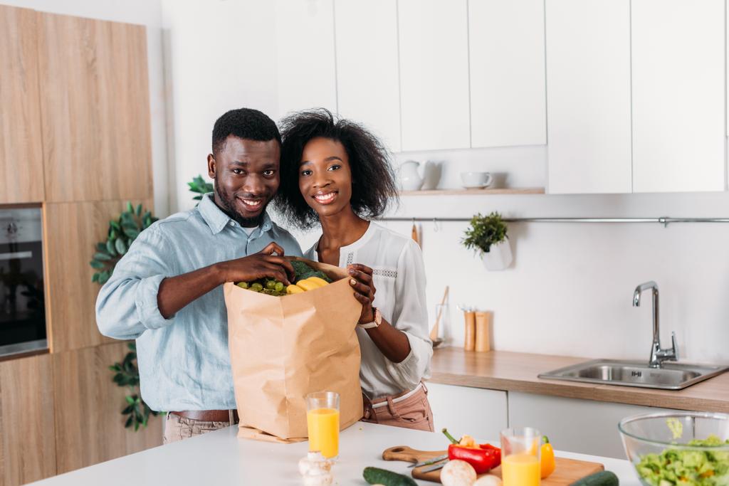 Sorridente coppia afro-americana che estrae uva dal sacchetto di carta con frutta
 - Foto, immagini