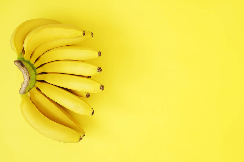 Kaunis minimalistinen tasainen lay koostumus kypsä tuoreita orgaanisia banaaneja käsi lämpimiä keltaisia värejä. Top View kopioi tilaa, lähikuva
. - Valokuva, kuva