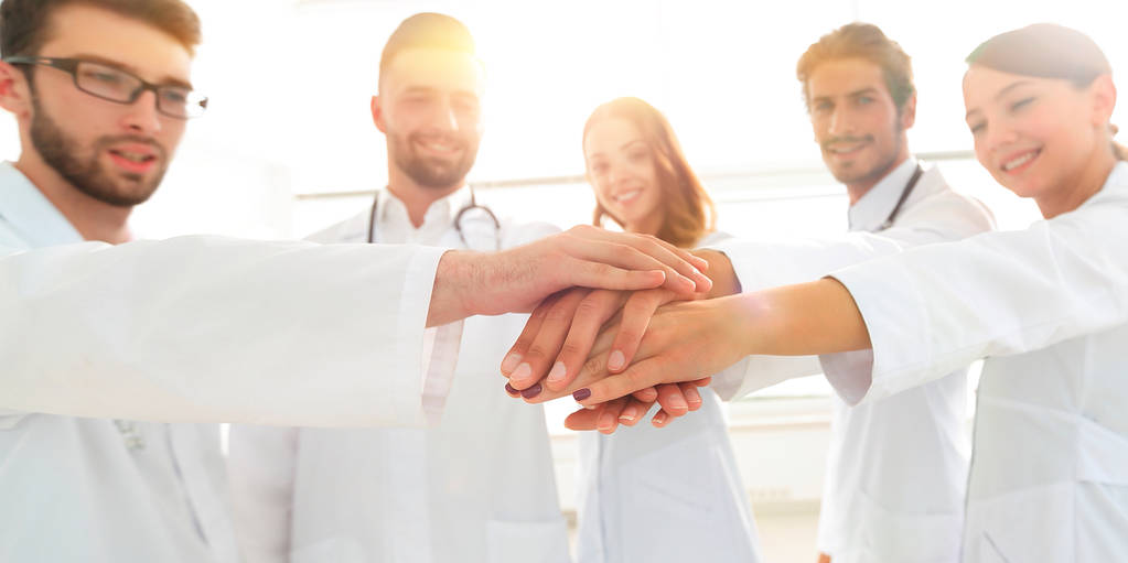 Artsen en verpleegkundigen in een medisch team stapelen handen - Foto, afbeelding