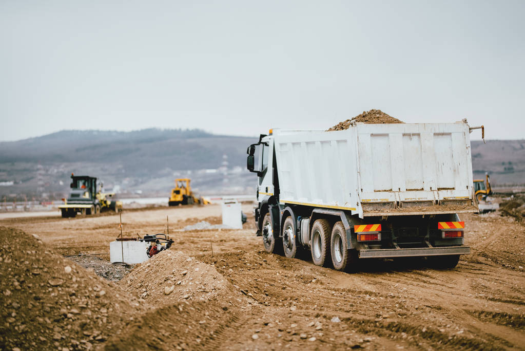 Camiones volquete industriales que trabajan en la construcción de carreteras, cargando y descargando tierra. actividad de maquinaria pesada
 - Foto, Imagen