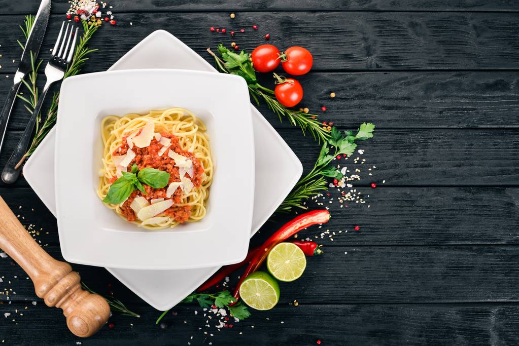 Italiaanse keuken. pasta met tomaten en Parmezaanse kaas. Op een houten achtergrond. Bovenaanzicht. Kopiëren van ruimte. - Foto, afbeelding