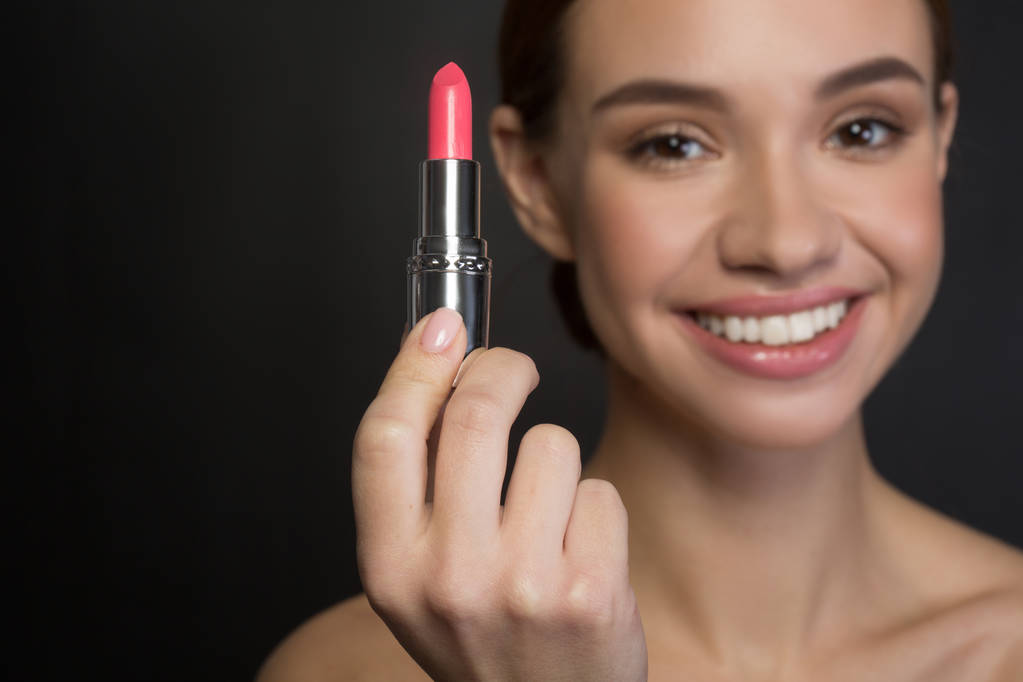 Positives Mädchen zeigt Make-up-Produkt - Foto, Bild