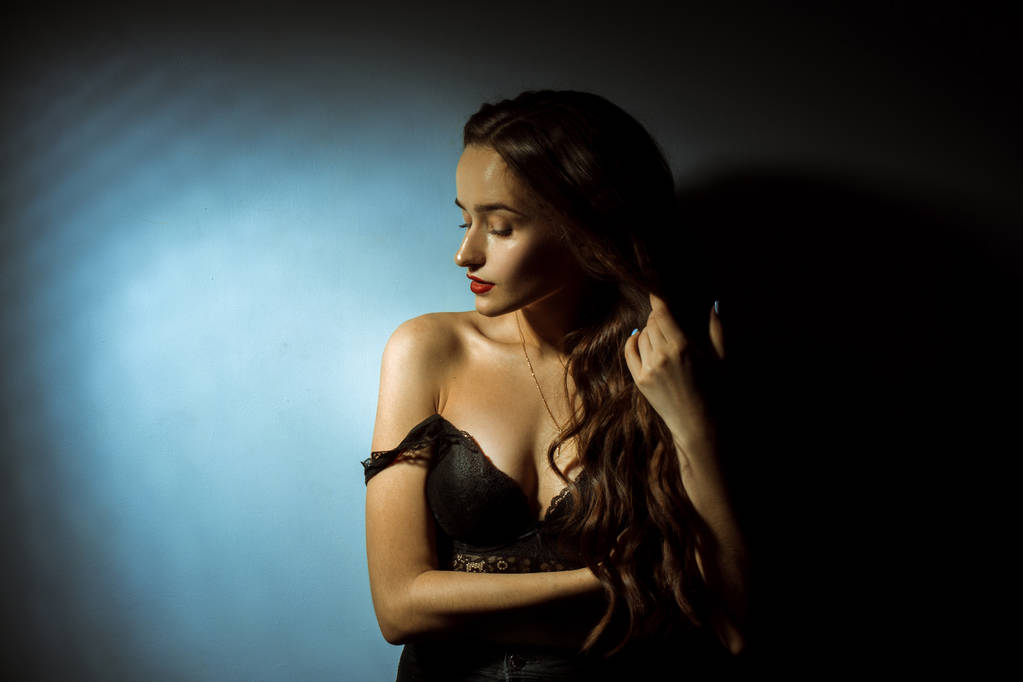 Prachtige dame met krullend kapsel in donkere studio - Foto, afbeelding
