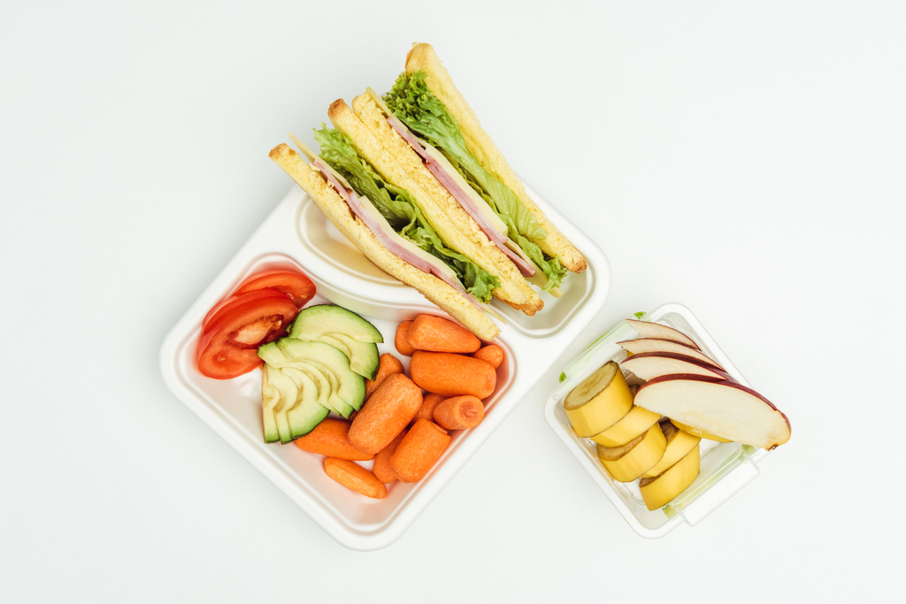 вид сверху на бутерброды, фрукты и овощи в упаковках, изолированных на белом
 - Фото, изображение