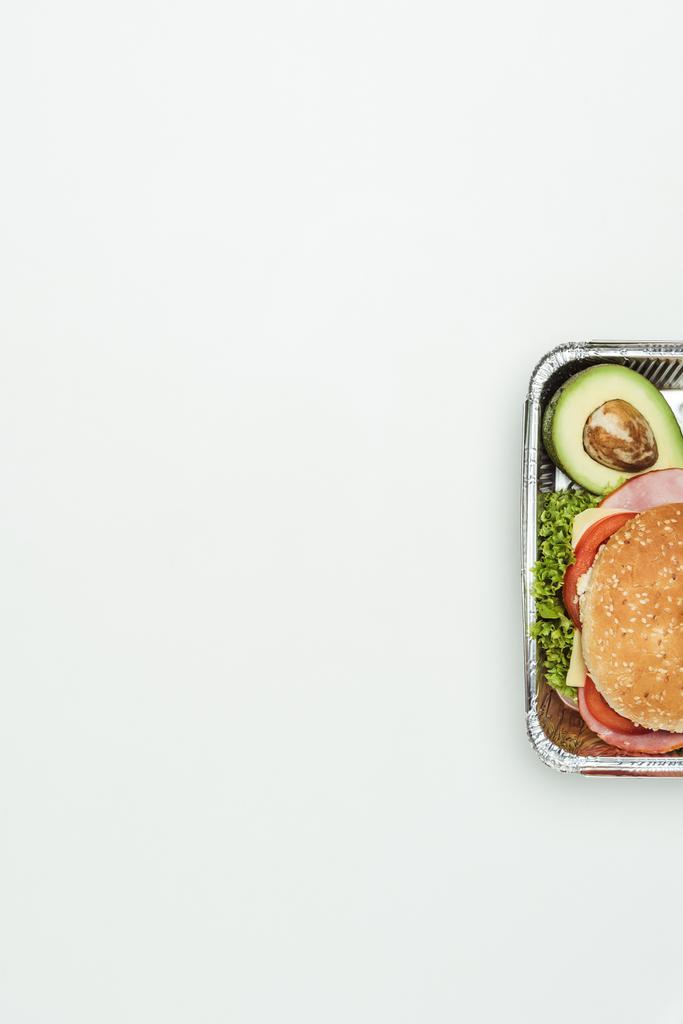 abgeschnittenes Bild von Burger mit Avocado in Lunchbox isoliert auf weiß - Foto, Bild