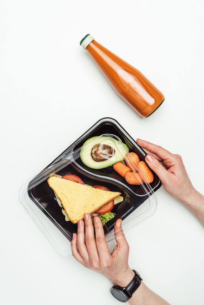 image recadrée de femme ouvrant boîte à lunch en plastique avec de la nourriture isolée sur blanc
 - Photo, image