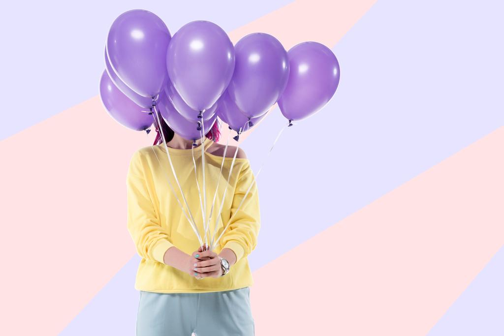 Frau bedeckt Gesicht mit Haufen Heliumballons auf kreativem Hintergrund - Foto, Bild