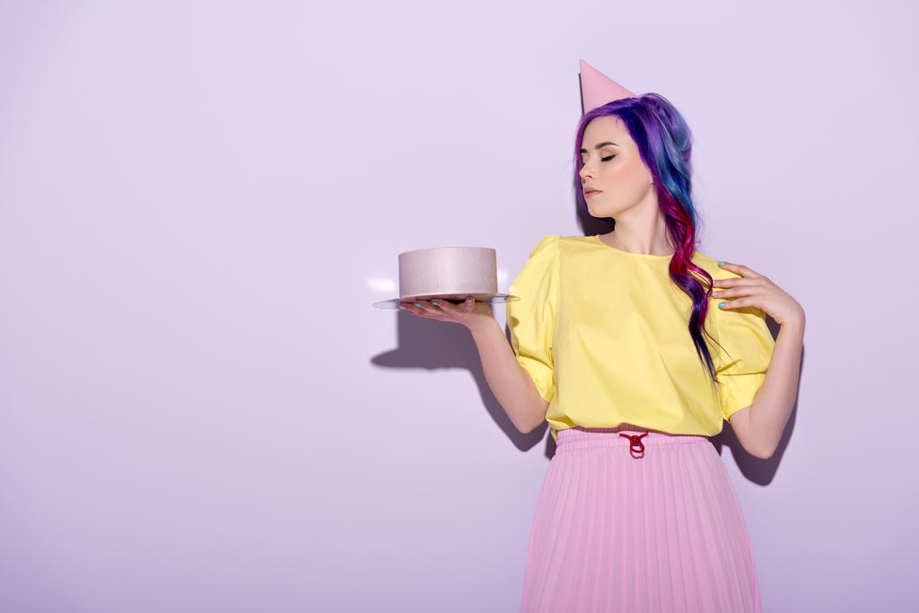 krásná mladá žena v klobouku stran s barevnými vlasy drží narozeninový dort - Fotografie, Obrázek