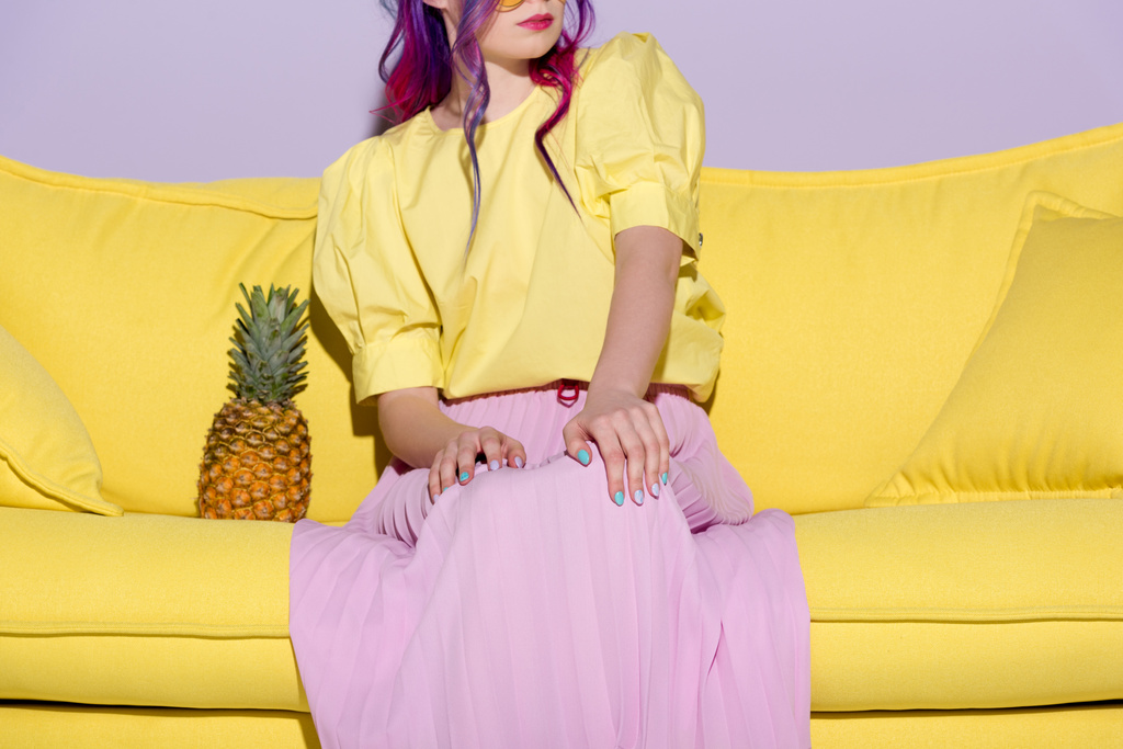 Oříznout záběr mladá žena sedící na žluté pohovce s ananasem - Fotografie, Obrázek