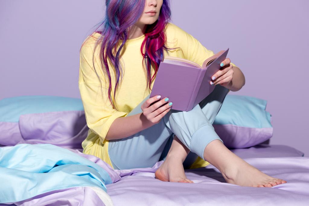 tiro cortado de mulher jovem com livro de leitura de cabelo colorido na cama
 - Foto, Imagem