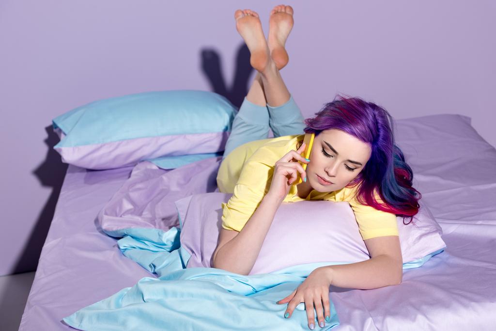 魅力的な若い女性のベッドで電話で話し - 写真・画像