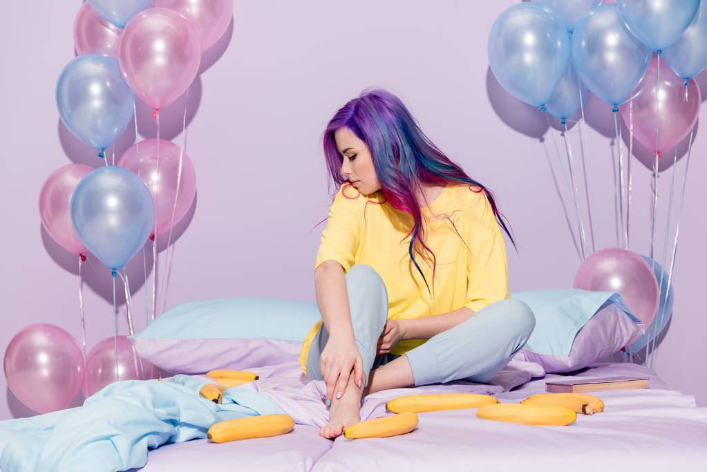 όμορφη νεαρή γυναίκα που κάθεται στο κρεβάτι με τις μπανάνες και μπαλόνια - Φωτογραφία, εικόνα