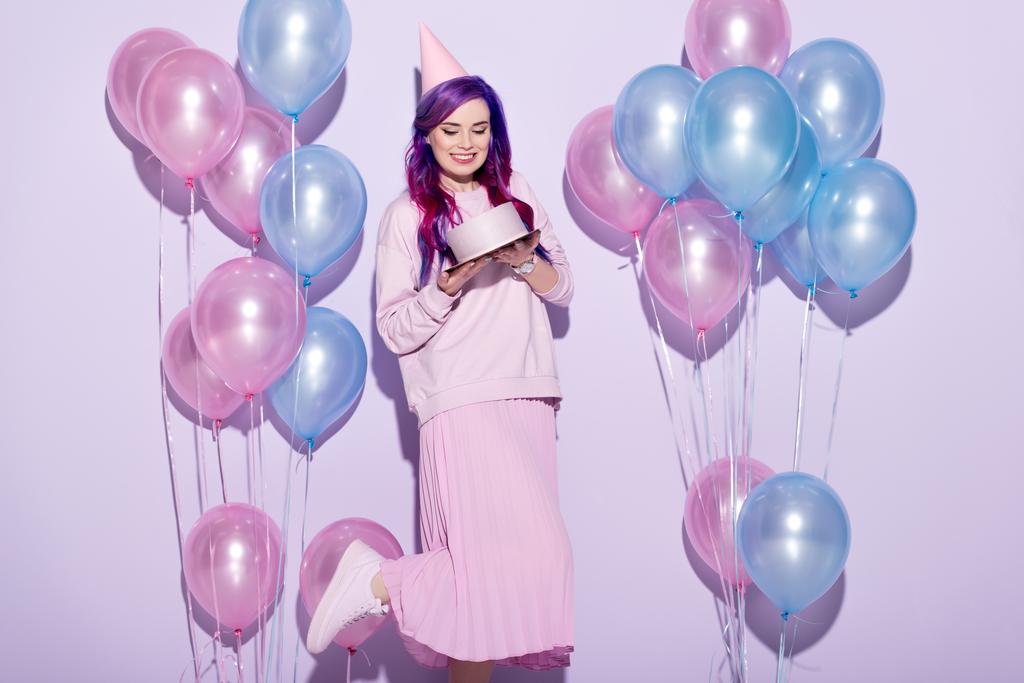 schöne junge Frau mit Geburtstagstorte und Partyhut auf rosa - Foto, Bild