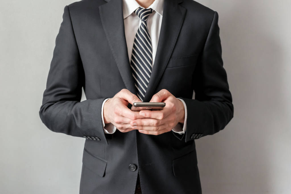 Un homme d'affaires confiant en costume écrit un message sur son smartphone
. - Photo, image
