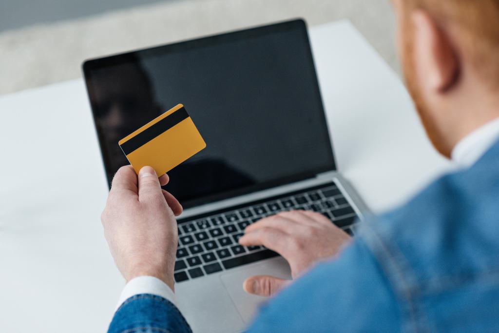 Чоловік платить за онлайн покупку з кредитною карткою та ноутбуком
 - Фото, зображення