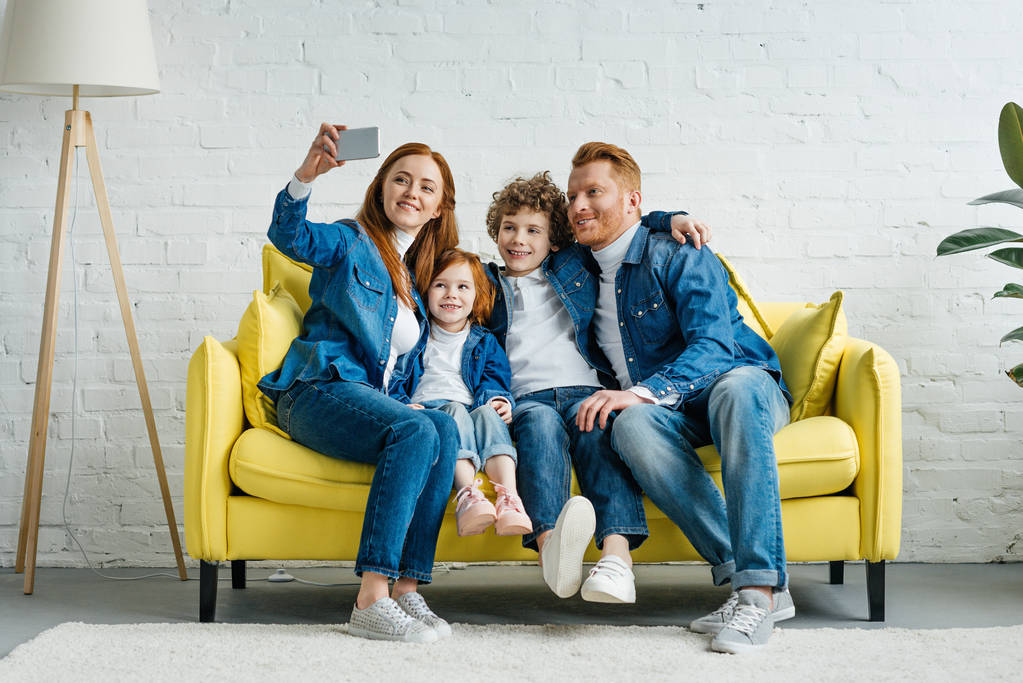 Szczęśliwa rodzina biorąc selfie siedząc na kanapie - Zdjęcie, obraz