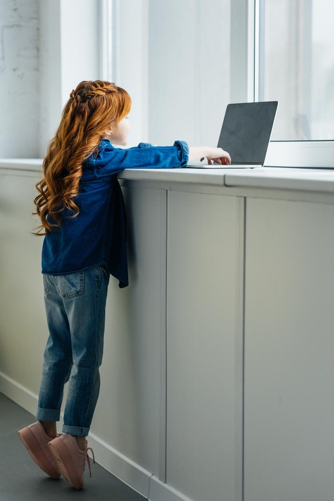 Adorable child reaching to laptop on windowsill - Photo, Image
