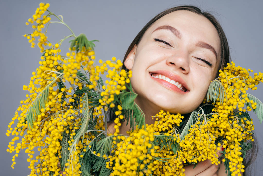 счастливая молодая девушка улыбается, счастливая весна, держа большой букет желтой мимозы
 - Фото, изображение