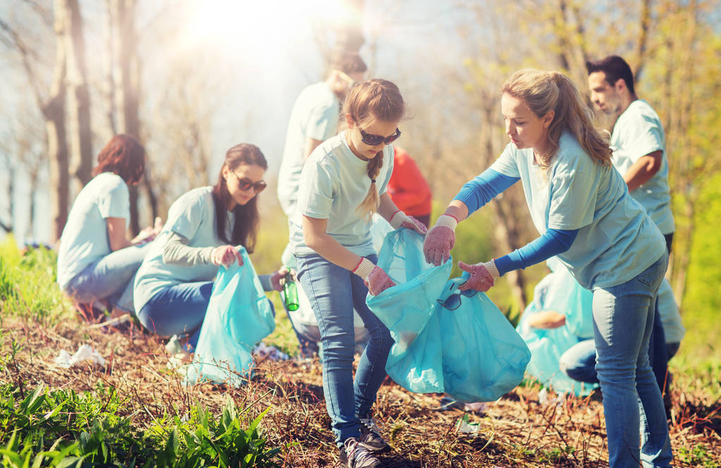 Freiwillige mit Müllsäcken säubern Parkfläche - Foto, Bild