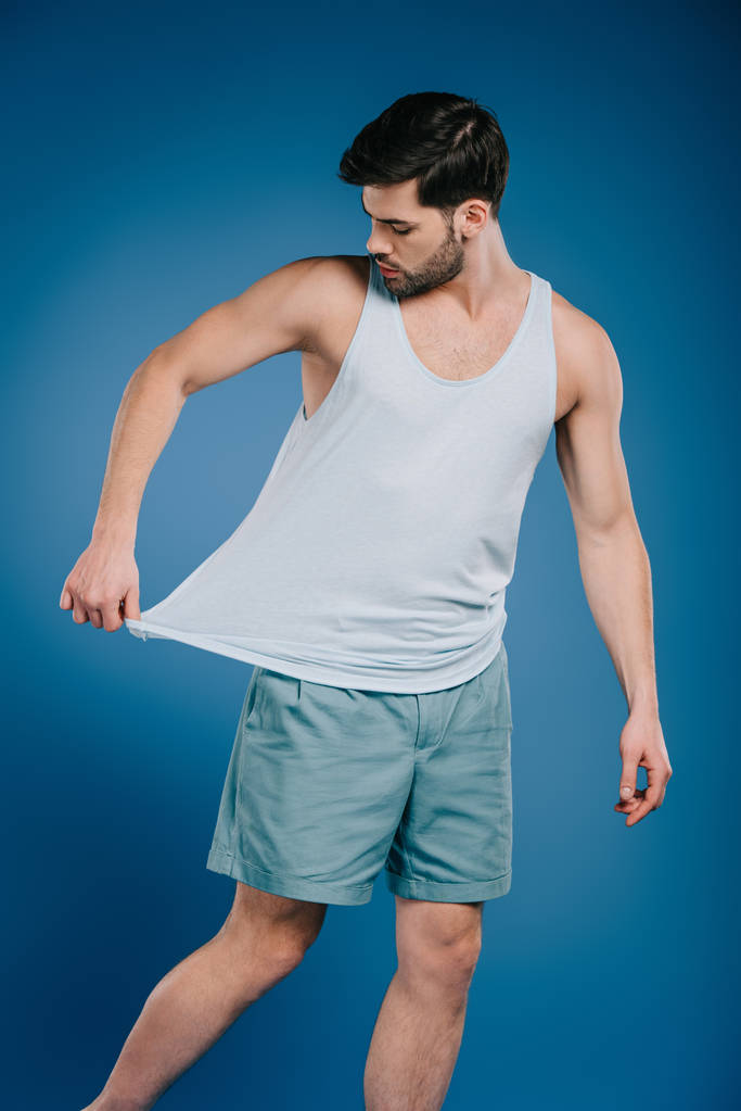 joven en pantalones cortos mirando singlet blanco en azul
 - Foto, imagen
