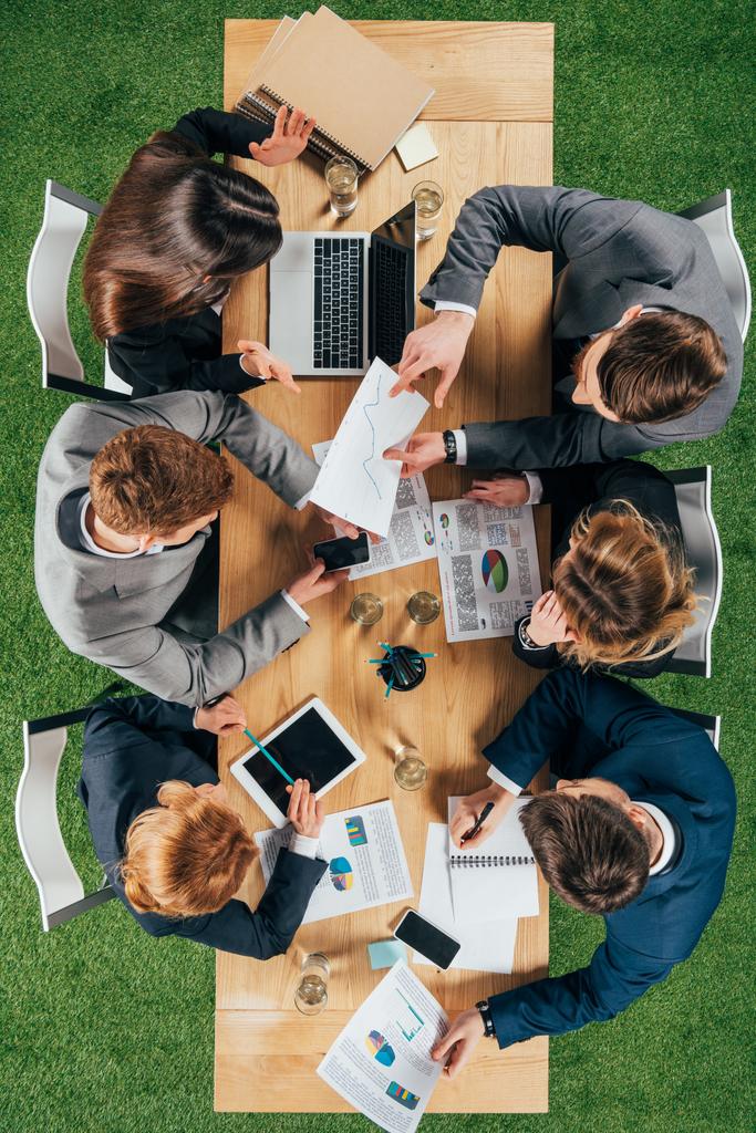 visión general de los empresarios teniendo discusión en la mesa con documentos y dispositivos en la oficina
 - Foto, imagen