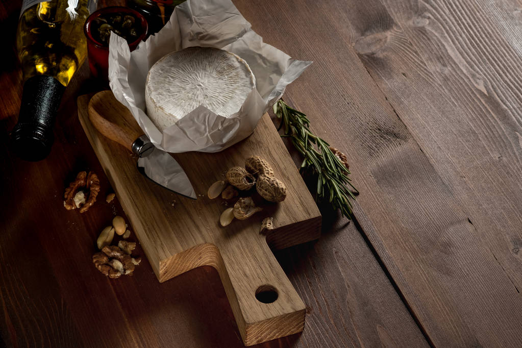 ρουστίκ επίπεδης lay με τυρί Μπρι για κοπή του σκάφους με βότανα και ξηρούς καρπούς σε καφετί ξύλινο τραπέζι, το top view με αντίγραφο χώρου - Φωτογραφία, εικόνα