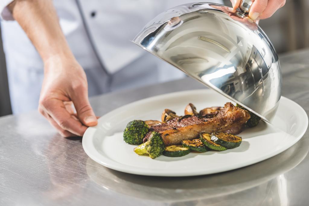 обрізане зображення відкриваючої пластини шеф-кухаря з тарілкою на кухні ресторану
 - Фото, зображення