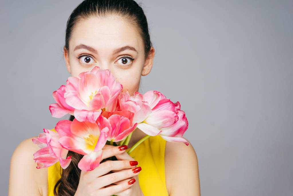 csinos fiatal lány meglepett, kezében egy csokor, illatos rózsaszín virágok - Fotó, kép