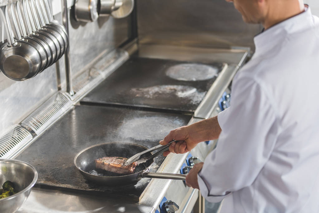 περικομμένη εικόνα του σεφ τηγάνισμα κρέατος σε κουζίνα εστιατορίου - Φωτογραφία, εικόνα