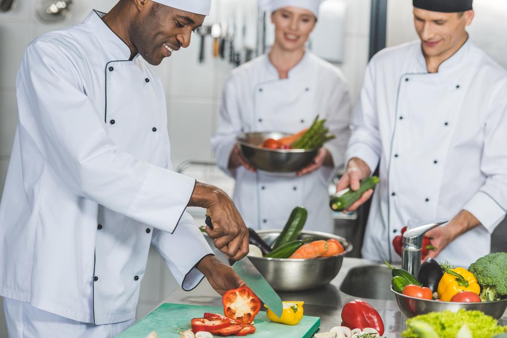 chefs multiculturales ensalada de cocina en la cocina del restaurante
 - Foto, imagen