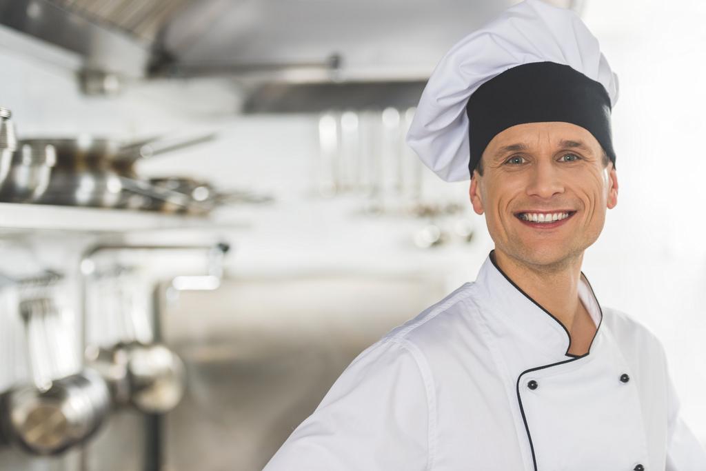 feliz guapo chef mirando la cámara en la cocina del restaurante
 - Foto, imagen