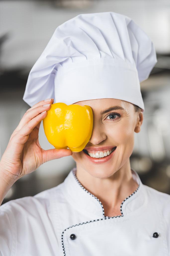 χαμογελώντας σεφ που καλύπτει το μάτι με πιπεριά σε κουζίνα εστιατορίου - Φωτογραφία, εικόνα