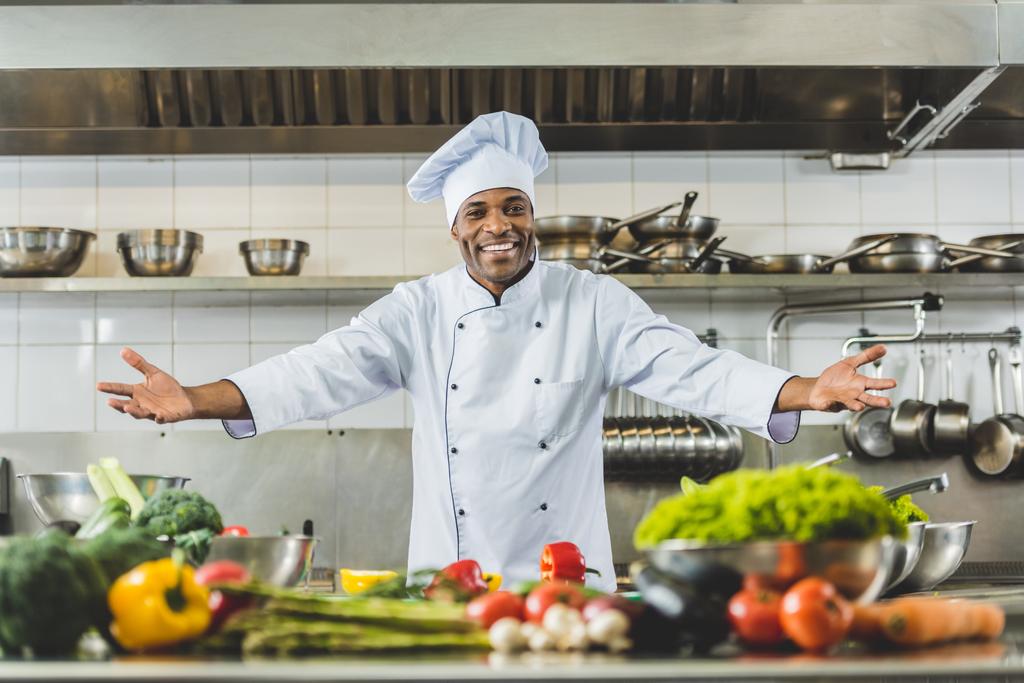 όμορφος Αφρικανικός Αμερικανός σεφ στέκεται με ανοιχτές αγκάλες σε κουζίνα εστιατορίου - Φωτογραφία, εικόνα