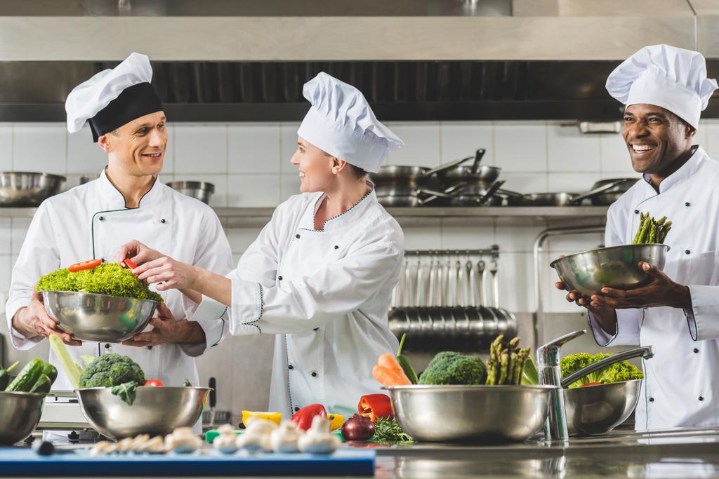 chefs multiculturales alegres cocina en la cocina del restaurante
 - Foto, imagen
