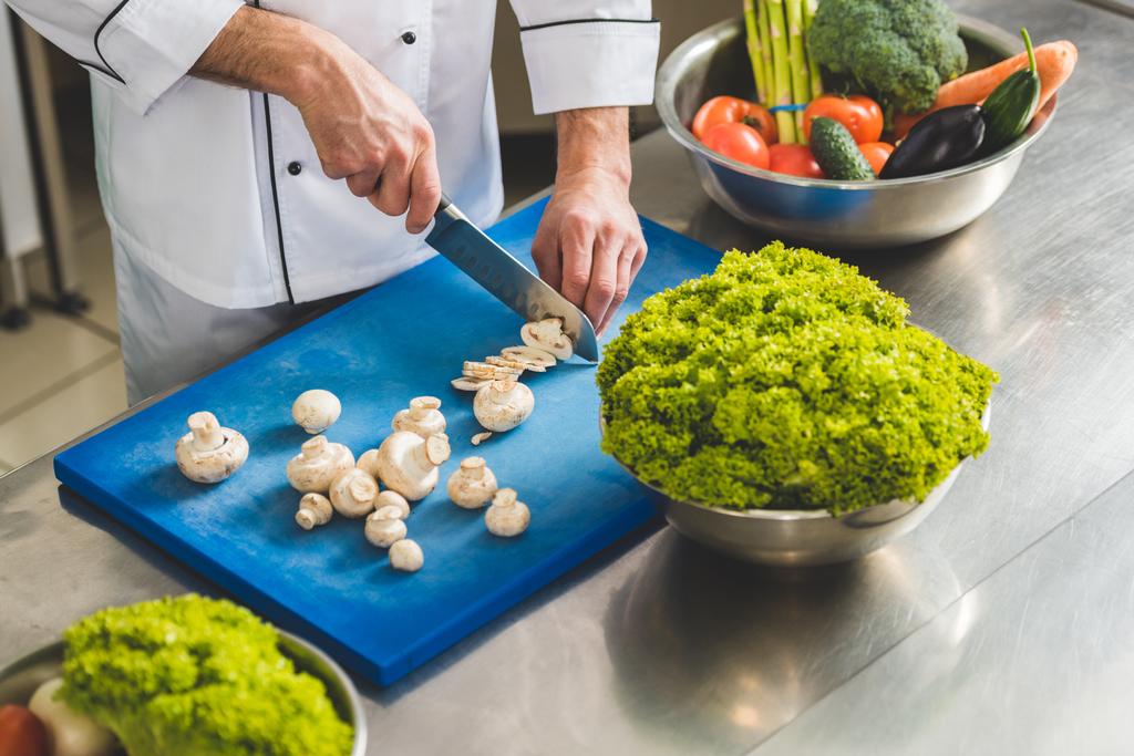 обрезанный образ шеф-повара, стригущего грибы на кухне ресторана
 - Фото, изображение