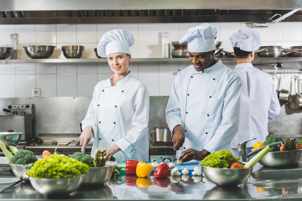 chefs multiculturais cortando legumes na cozinha do restaurante
 - Foto, Imagem