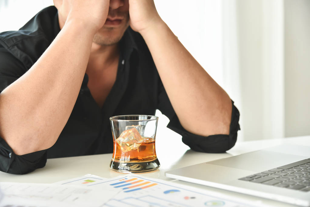 Un homme d'affaires alcoolique tient un verre de whisky
. - Photo, image