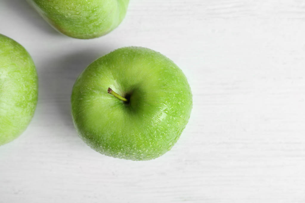 Свіжі зелені яблука з краплями води на білому столі, вид зверху
 - Фото, зображення