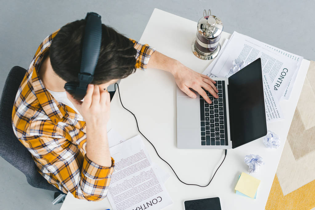 ogólny widok człowieka w pracy na laptopie przez stół w biurze lekkie słuchawki - Zdjęcie, obraz