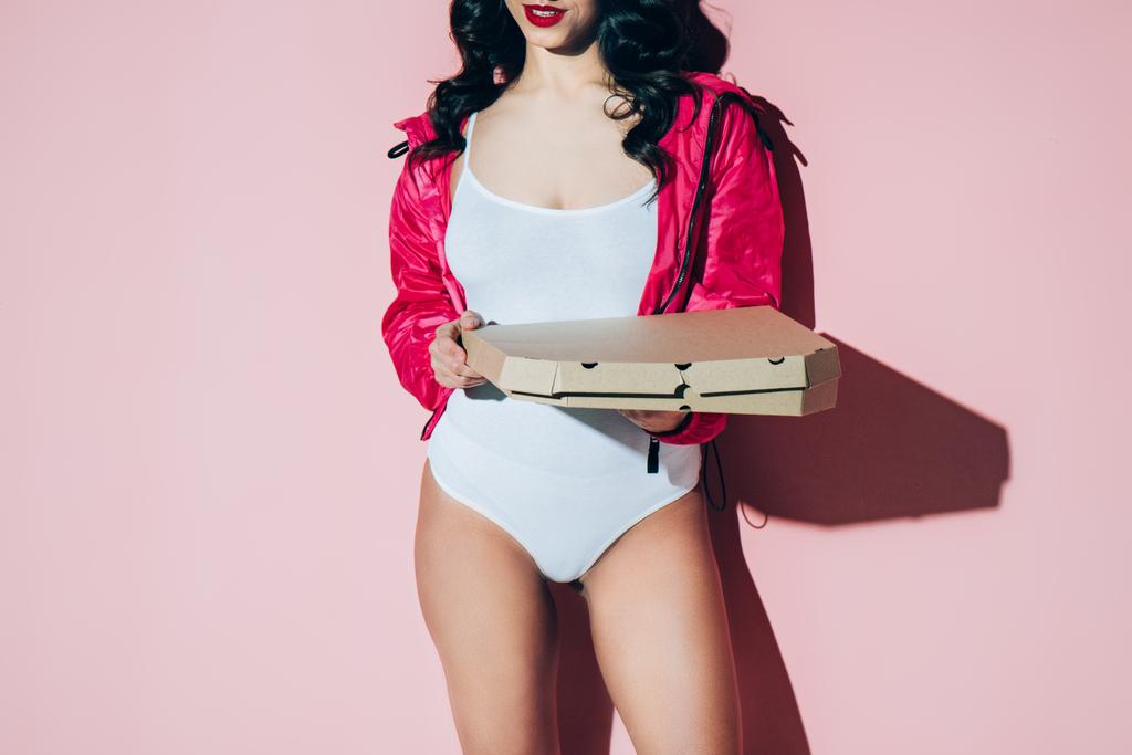 partial view of woman in white bodysuit holding delivery box with pizza on pink backdrop - Photo, Image
