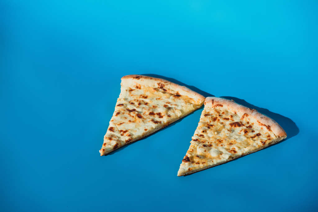 vista de perto de pedaços de pizza cozida isolada em azul
 - Foto, Imagem