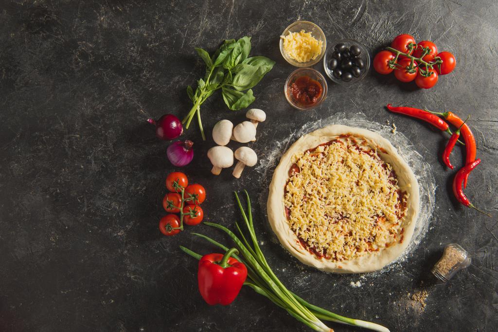 vista dall'alto della pizza cruda italiana e degli ingredienti freschi sulla superficie scura
 - Foto, immagini