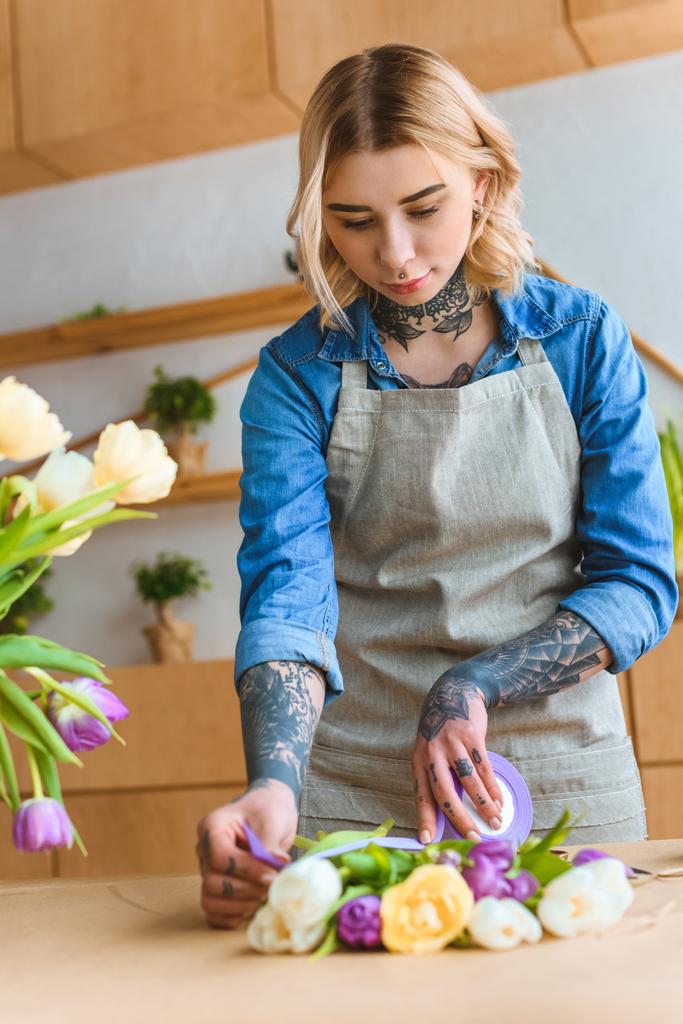 beautiful young florist arranging tulip flowers at workplace - Photo, Image
