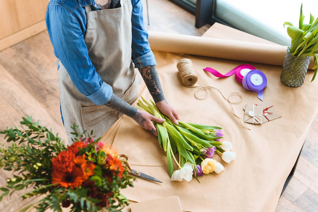 обрезанный снимок флориста в фартуке, работающего с красивыми цветами тюльпана
 - Фото, изображение