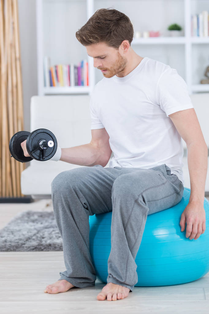 attractive young man with swiss ball doing exercises at home - Photo, Image