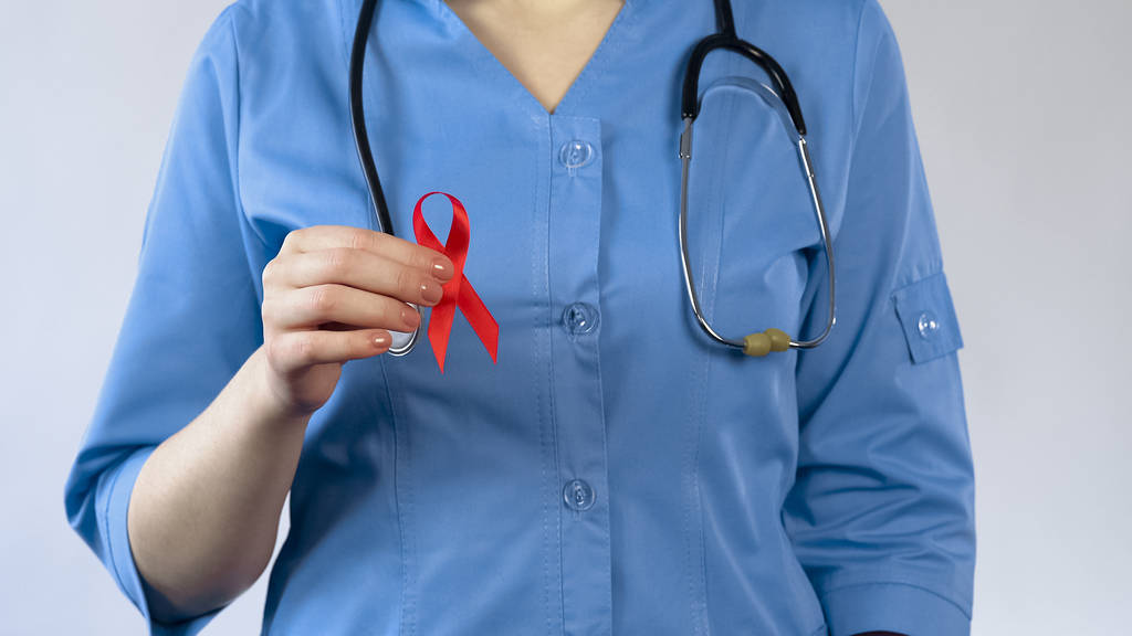 Γυναίκα γιατρό δείχνει κόκκινη κορδέλα, σύμβολο ευαισθητοποίησης του Aids, αφροδίσια ασθένεια κίνδυνο - Φωτογραφία, εικόνα