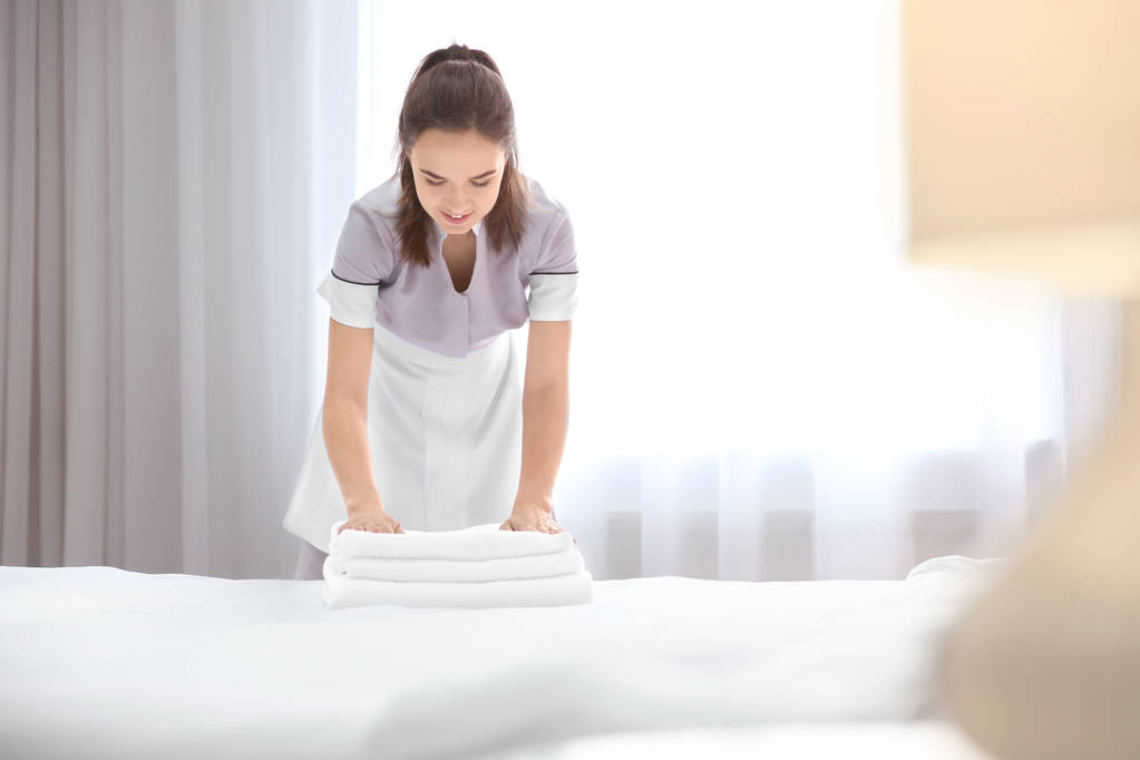 Mladá služka s zásobník ručníků v hotelovém pokoji - Fotografie, Obrázek